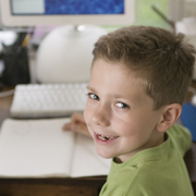 young boy turned around at a computer with a notepad